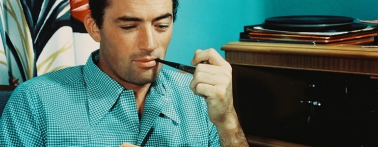 Gregory Peck, une pipe en main, feuillette un livre, en écoutant de la musique grâce à un tourne-disque