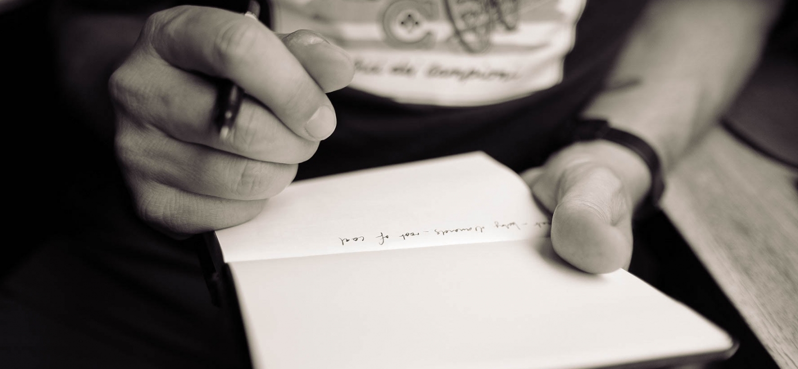 Photographie noir et blanc d'un homme écrivant sur un carnet